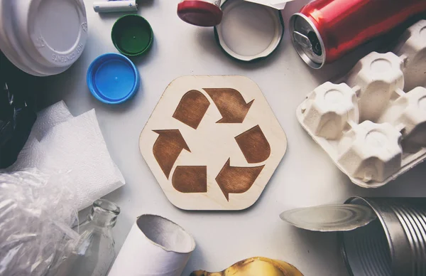 A lot of different garbage on the table and the recycling icon b — Stock Photo, Image