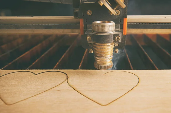 Laser cutting machine is cutting hearts in the wooden plank — Stock Photo, Image