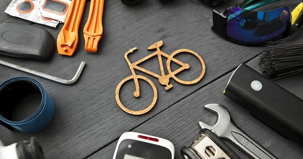 Um monte de acessórios de bicicleta diferentes deitado na mesa de madeira aro — Fotografia de Stock