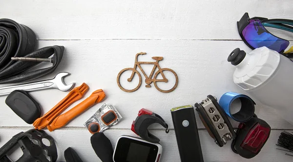 A lot of different bicycle accessories lying on wooden table aro — Stock Photo, Image