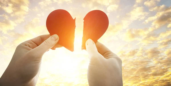 The woman is holding two parts of broken heart in her hads in fr — Stock Photo, Image