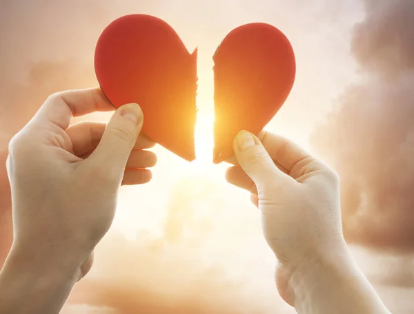 The woman is holding two parts of broken heart in her hads in fr — Stock Photo, Image