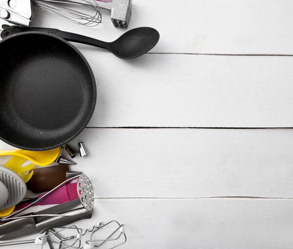 Lots of different kitchen utensils on the wooden table