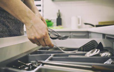 Kadın mutfak malzemelerini mutfak malzemeleriyle birlikte raftan alıyor.