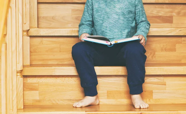 Çocuk Evdeki Ahşap Merdivenlerde Oturmuş Kağıt Kitap Okuyor — Stok fotoğraf