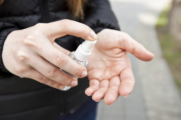 The young woman sanitizing her hand by sanitizer