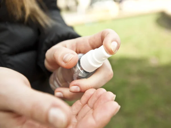 The young woman sanitizing her hand by sanitizer