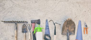 Beton zeminde bir sürü kullanılmış ve kirli bahçe aletleri var.