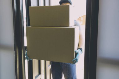 Kurye, plastik eldiven ve tıbbi maske takarak kutuları eve getiriyor.