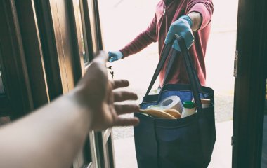 Teslimatçı adam çantayı marketten kadına ve evine veriyor.