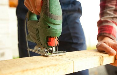 Adam yapbozla tahta kesiyor.