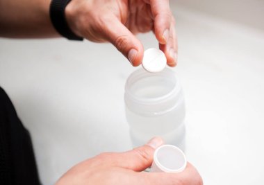Bisikletçi izotonik içeceği yapıyor. Alevli tabletleri plastik şişenin içine koyuyor.