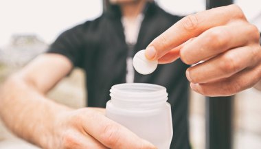 Bisikletçi izotonik içeceği yapıyor. Alevli tabletleri plastik şişenin içine koyuyor.
