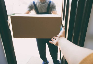 Kurye eve plastik eldiven giyerek karton kutuyu getiriyor.