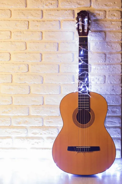 Guitarra con guirnaldas iluminadas sobre fondo de ladrillo blanco — Foto de Stock
