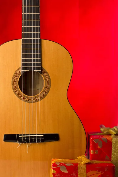 Guitarra y cajas de vacaciones sobre fondo rojo de Navidad — Foto de Stock