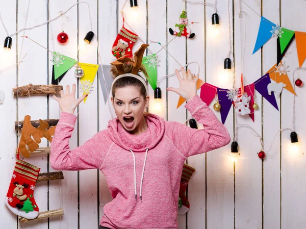 若いとクリスマスの装飾とガーランドの壁の近くの枝角を持つ幸せな白人女 — ストック写真