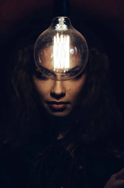 Mysteriöses Foto einer Frau mit Glühbirne. Porträt im Dunkeln. Gefährliches Mädchen. — Stockfoto