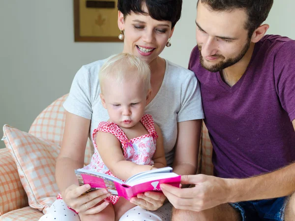 Moeder, vader en dochter lezen van een boek. Familie zittend op de Bank. — Stockfoto