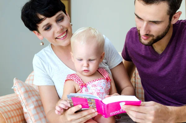 Moeder, vader en dochter lezen van een boek. Familie zittend op de Bank. — Stockfoto