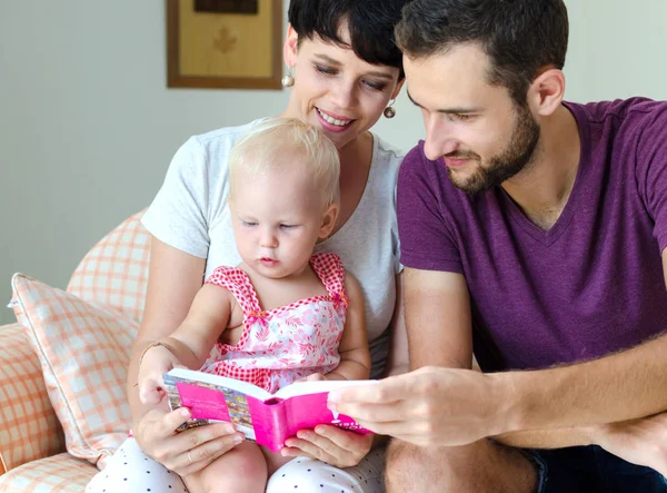 Moeder, vader en dochter lezen van een boek. Familie zittend op de Bank. — Stockfoto