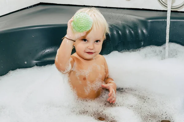 Koupelna je plný pěny, dítě je plavání. — Stock fotografie
