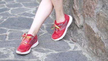 Spor ayakkabı, bir kız bir parapetin üzerinde oturuyor.