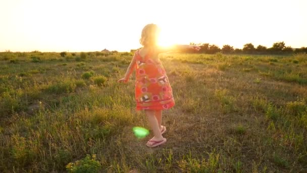 Une petite robe de fille tourne dans les rayons du soleil couchant . — Video