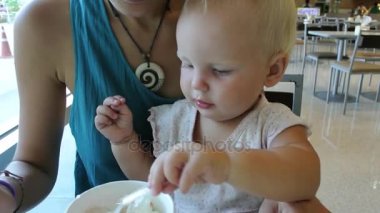 Anne ve bebek bir kafede kahvaltı. Aile dondurma yiyor.