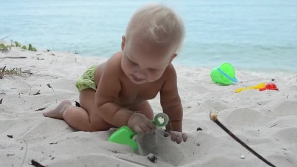 Uma criança está brincando na areia na costa . — Vídeo de Stock