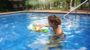 Anne ve kızı tatil havuzunda yüzüyor.