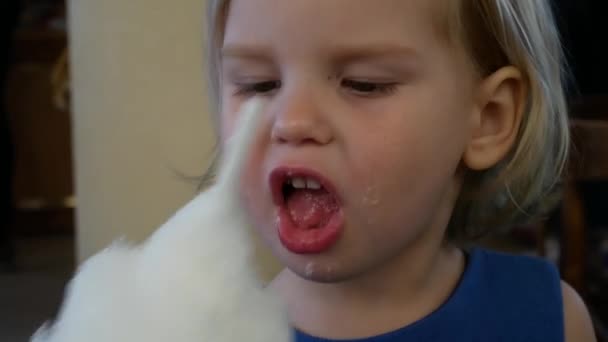 En liten flicka äter söta bomull. — Stockvideo