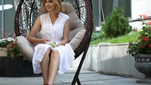 Дівчина в білій сукні їсть зелене яблуко . — стокове відео