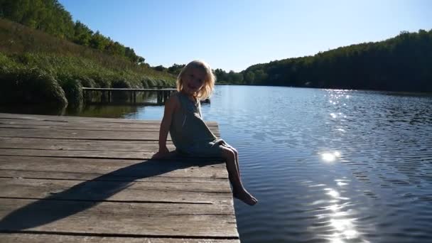 A menina no cais se alegra com o sol . — Vídeo de Stock