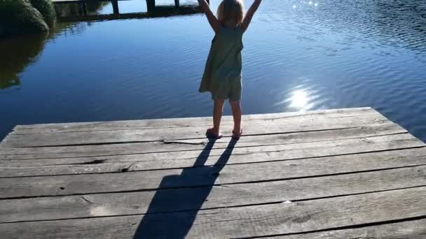 Das Mädchen auf der Seebrücke freut sich in der Sonne. — Stockvideo