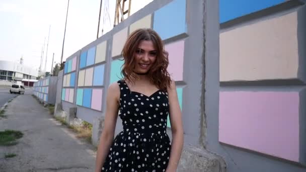 Una chica en zapatillas y un vestido está caminando por la ciudad . — Vídeo de stock