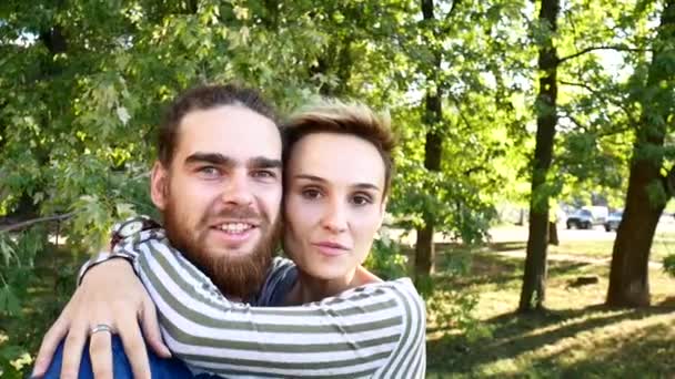 Young couple doing selfie. A guy with a beard and a girl with a short hair cut themselves off and fool around at the camera. — Stock Video