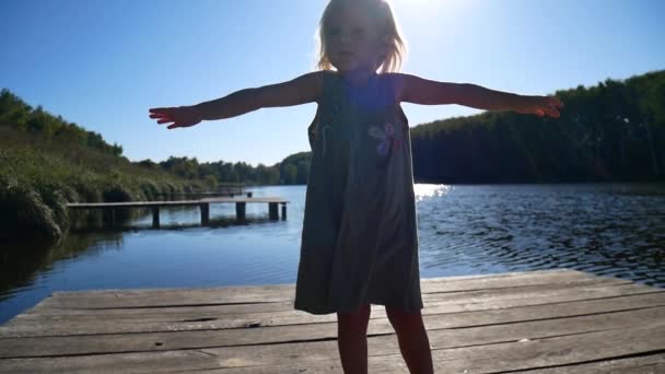 Das Mädchen auf der Seebrücke freut sich in der Sonne. — Stockvideo