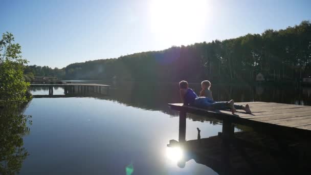 Paisaje cerca del lago. Cañas y madre con hija en el muelle . — Vídeos de Stock