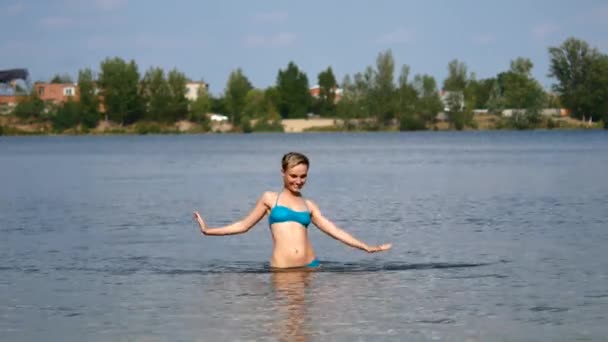 Una chica en traje de baño azul. Una mujer disfruta del verano y el sol, se baña en el lago . — Vídeo de stock