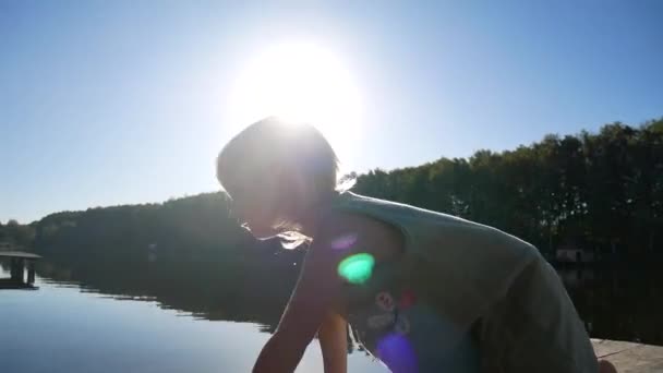 Flickan på piren jublar i solen. — Stockvideo