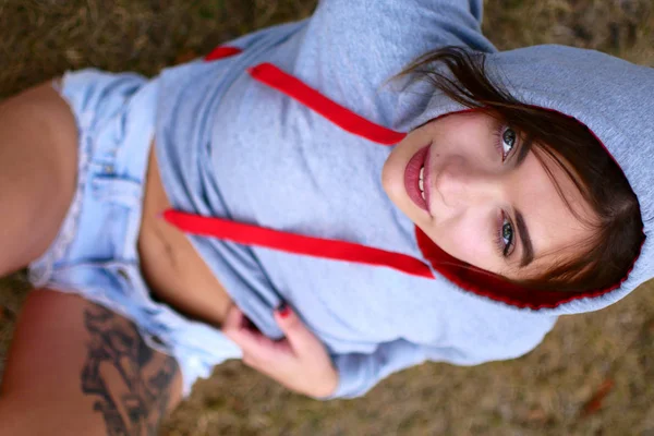 Giovane donna seducente in pantaloncini di jeans corti. Fotosessione sexy nel parco . — Foto Stock
