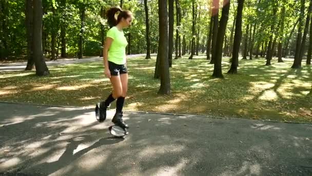 Joven chica hermosa haciendo deportes en el parque. Una mujer salta en zapatos especiales para la aptitud . — Vídeo de stock