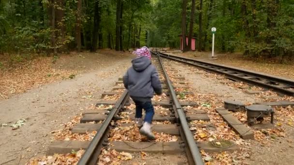 Маленькая девочка идет по рельсам. Осенний лес . — стоковое видео