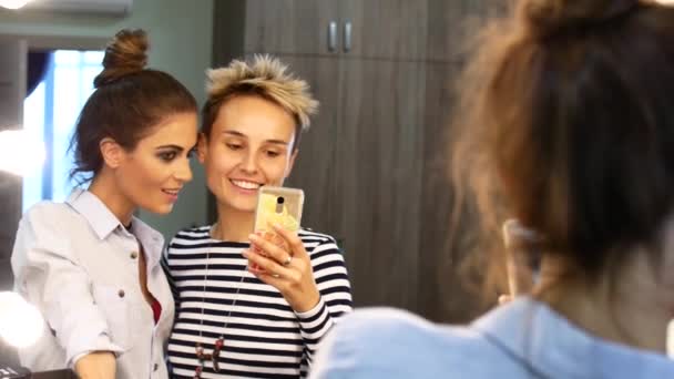 Dois amigos fazem uma selfie perto do espelho. Meninas tolo em torno de rir e tirar fotos . — Vídeo de Stock