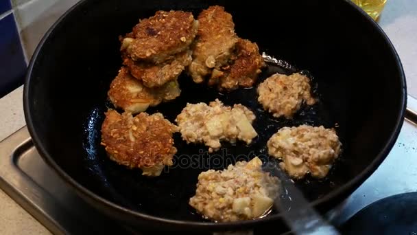 O cozinheiro prepara as costeletas em uma frigideira. Pequenas panquecas são fritas em óleo . — Vídeo de Stock