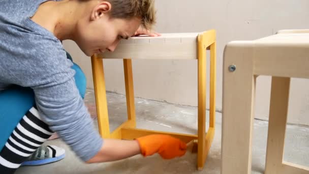 A girl is painting a chair. Repair in the apartment with your own hands. — Stock Video