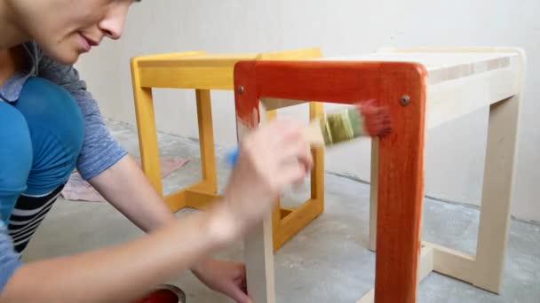 Een meisje is het schilderen van een stoel. Reparatie in het appartement met je eigen handen. — Stockvideo