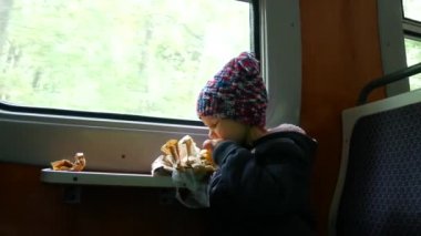Çocuğun pencerenin yakınındaki tren. Kız tren arabada oturan bir pasta yiyor.