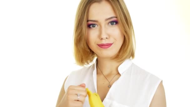 Een vrouw is het eten van een banaan. Mooi meisje op een witte achtergrond. — Stockvideo